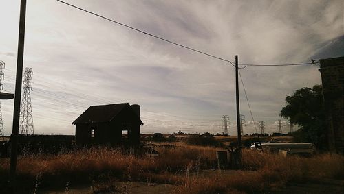 Electricity pylon against cloudy sky