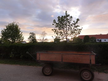 Cars parked on road against cloudy sky at sunset