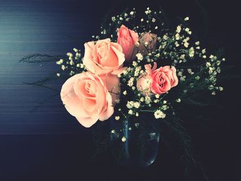 Close-up of rose bouquet in vase against black background