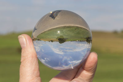 Cropped image of person holding ice cream in front of glass