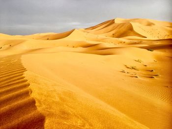 Sand dunes in desert against sky