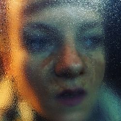 Close-up of thoughtful woman seen through window