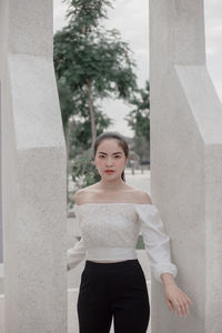 Portrait of woman standing by columns