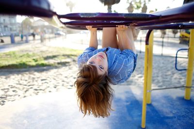 Portrait of teenage girl climbing ladder on playground