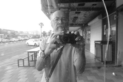 Rear view of man photographing on street