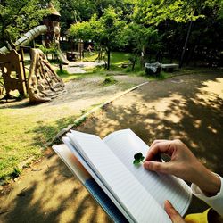 Close-up of hand on table against trees