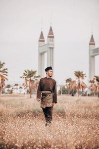 Woman walking on field against building