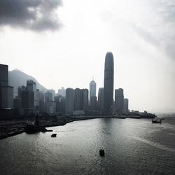 Sea and buildings in city against sky