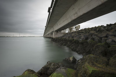 Bridge over river and stones against sky