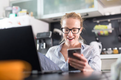 Businesswoman using smart phone sitting at home