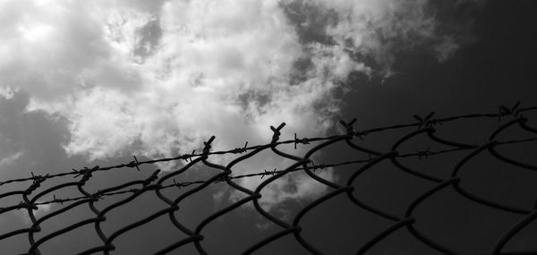 Low angle view of silhouette fence against sky