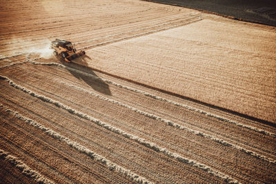 Combine harvester working at sunset from aerial view.