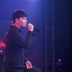 Side view of young man standing at music concert