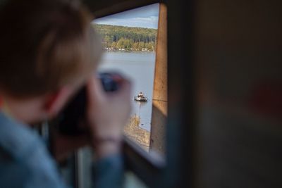 Rear view of woman looking through window