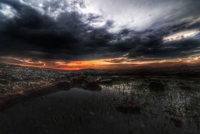 Scenic view of sea against dramatic sky during sunset