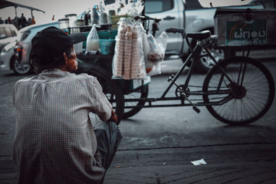 Rear view of a woman sitting on road