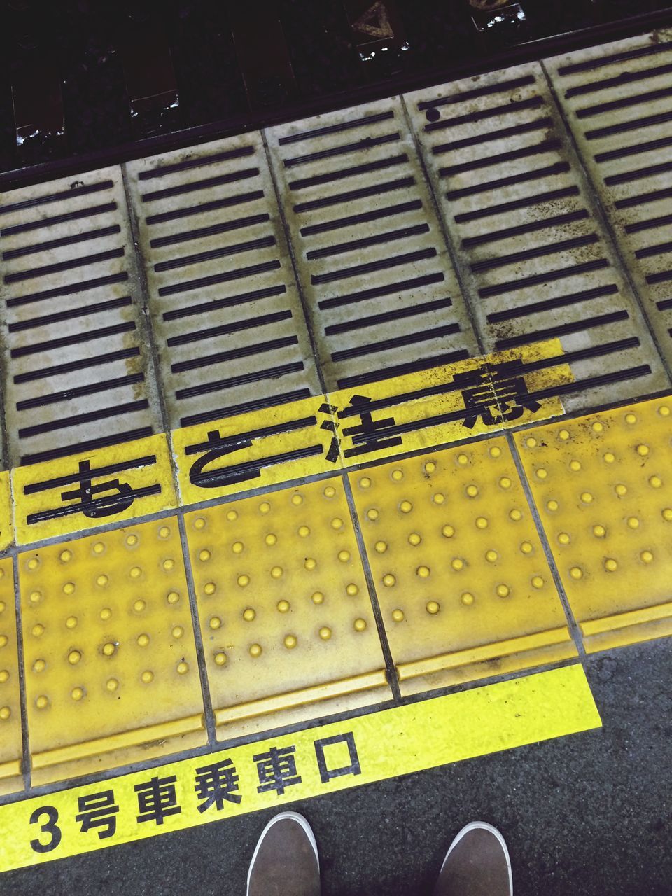 text, communication, western script, high angle view, capital letter, guidance, yellow, low section, street, sign, close-up, road marking, part of, arrow symbol, shoe, indoors, one person, number, direction, pattern