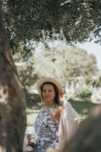 Portrait of young woman standing against trees