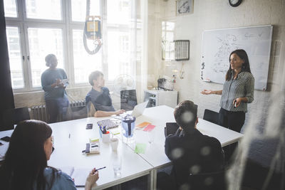 Businesswoman explaining business strategy to colleagues during meeting in creative office