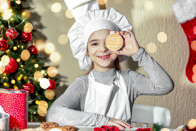 Portrait of young woman holding christmas tree at home