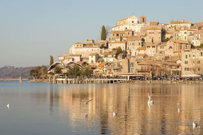 View of buildings by lake against clear sky