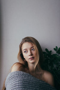 Beautiful young woman against wall at home