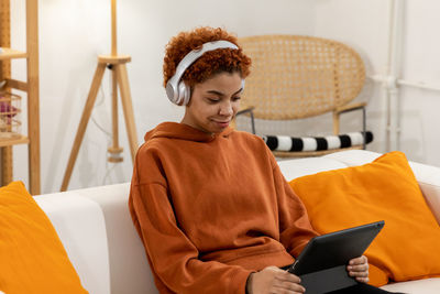 Portrait of young woman sitting on sofa at home