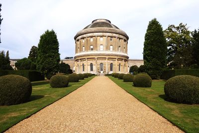 Footpath leading towards historical building against sky