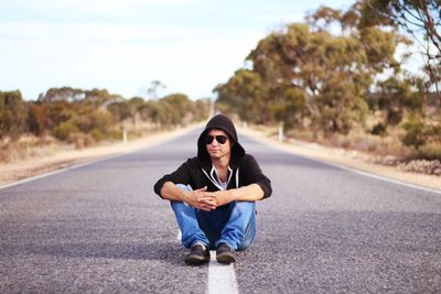 Portrait of young woman sitting on road