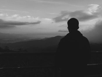Rear view of silhouette man looking at mountains against sky