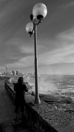 Rear view of woman standing by sea against sky