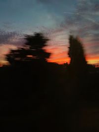 Silhouette trees against dramatic sky during sunset