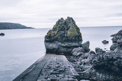 Rock formation on sea shore against sky