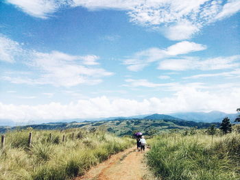 Rear view of man walking on road against sky