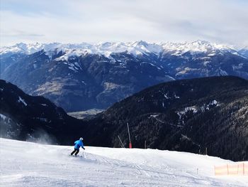 Man skiing on snowcapped mountain against sky