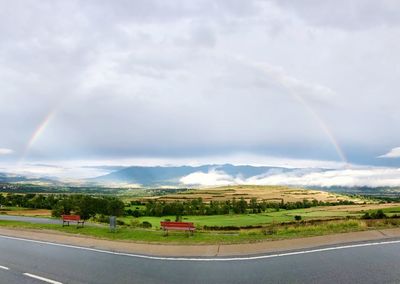 Scenic view of rainbow over road against sky