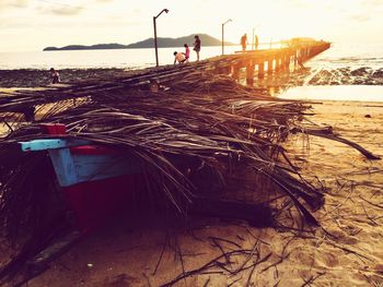 Man working on fishing net at beach during sunset