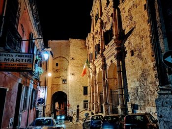 People on street amidst buildings in city at night