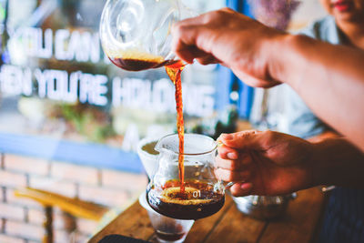 Midsection of man pouring coffee in glass