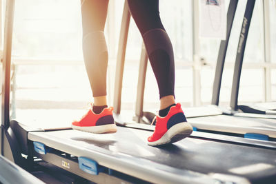 Low section of woman running on treadmill in gym