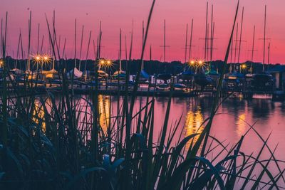 Sailboats moored in lake against sky during sunset