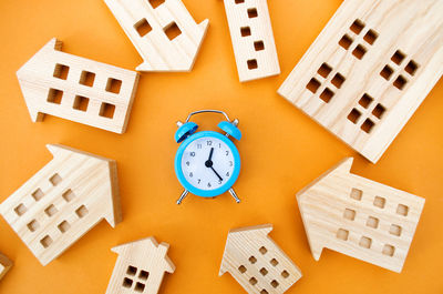 A blue alarm clock and many wooden houses around. mortgage and loan concept.