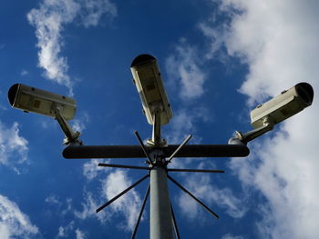 Low angle view of security cameras against sky