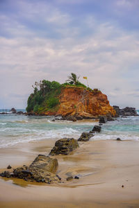 Rock formation on beach against sky