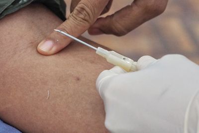 Cropped hands of doctor injecting patient in hospital