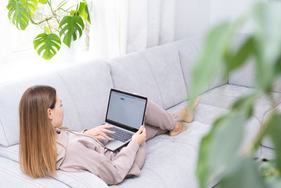 High angle view of woman using laptop while sitting on sofa