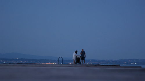 People on sea against clear blue sky