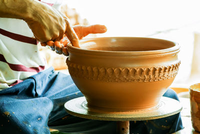 Midsection of potter making clay container in workshop