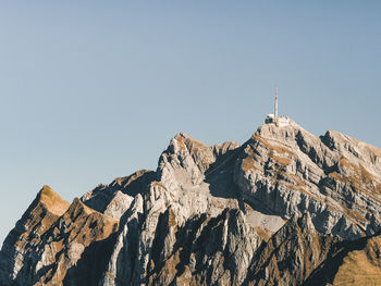 Low angle view of rocks and mountain against clear sky