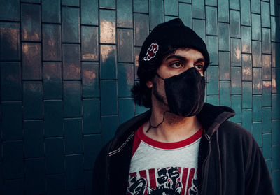 Portrait of young man standing against wall